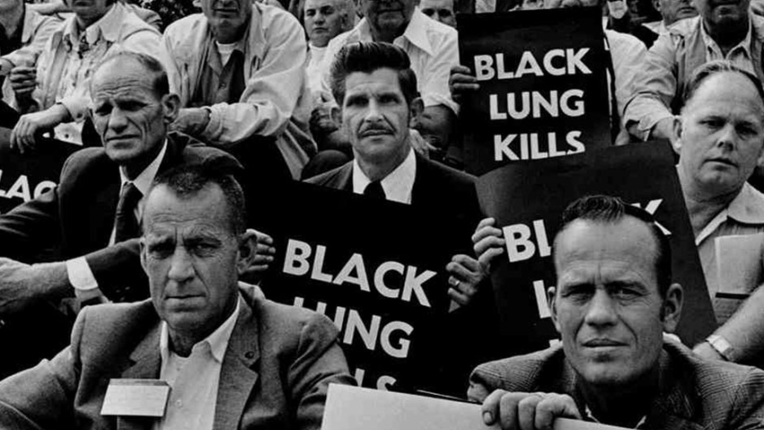Coal miners hold Black Lung Kills posters during a protest