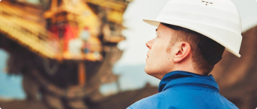 man wearing a hulmet looking to inspect a mine equipment