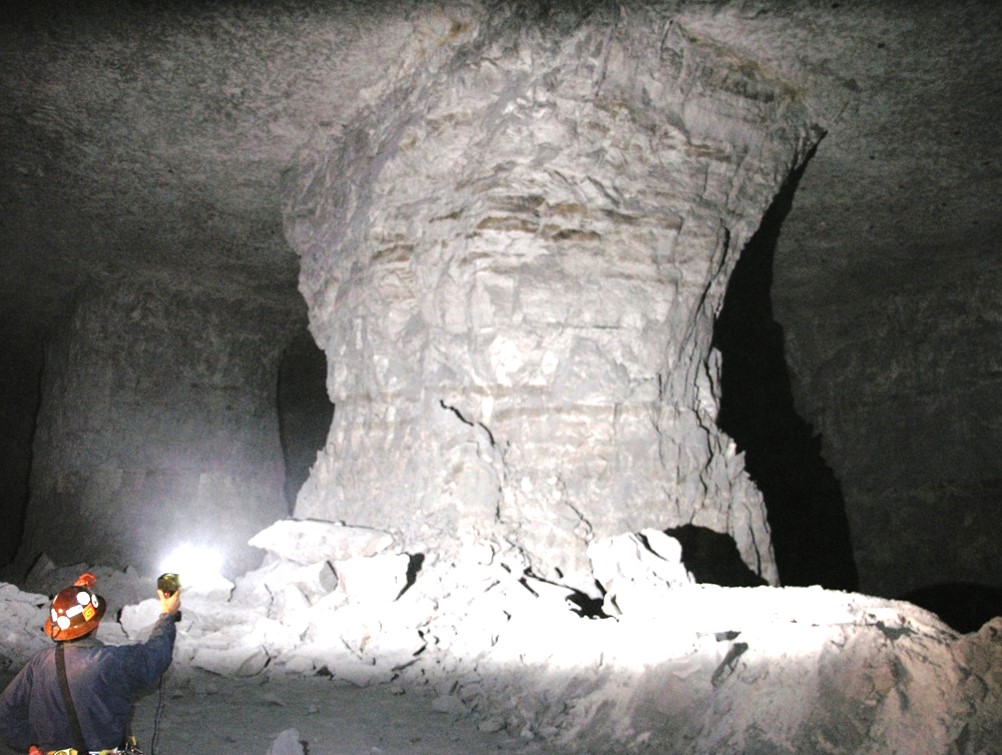 Inspector in a mine inspecting a pillar using a flash light