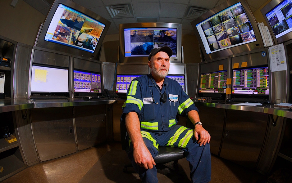 Miner setting down surrounded by monitors previewing mine data