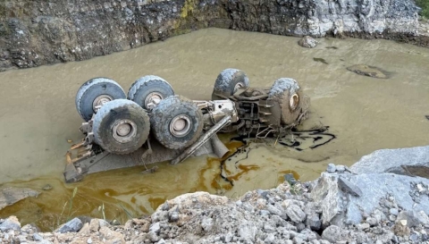Accident scene where a miner died after the haul truck he was driving went over a berm along the haul road, over a highwall, and overturned into water in the pit.