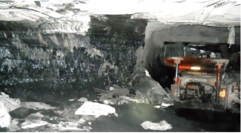 Accident scene where a miner was fatally injured when an overhang along the mine rib fell, striking the miner and pushing him against the canopy of a twin boom roof bolting machine.