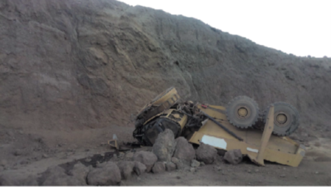 Accident scene where a miner died when the haul truck he was operating traveled through a berm and over an approximately forty-foot highwall to the bench below.