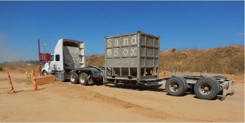 White Truck with a trailer with a steal sand box on it.