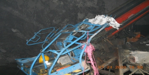 Accident scene where two miners were loading explosives from inside an aerial lift’s basket when the basket jolted upward into the mine roof, causing the death of one of the miners.