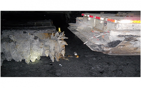highlighted: the space between a battery-powered maintenance scoop and the cutting head of a continuous mining machine
