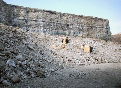 A front-end loader partially covered by rock after a blast