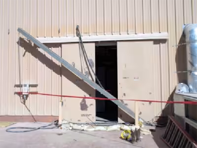 Metal sliding double doors with a cable tray hanging down diagonally across the front.
