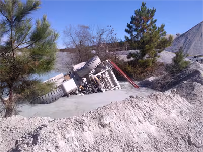 An overturned haul truck in a settling pond that is divided by a berm.