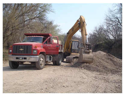 A truck parked beside the arm of the excavator. With the bucket of the excavator so close to the truck and knowing its angle of rotation, the photo shows how the bucket could have pinned the victim against the truck.