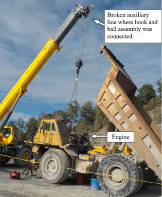 Accident scene where a miner died while using a crane to remove a haul truck engine.  The auxiliary line broke, causing the hook and ball assembly to fall and strike the miner.