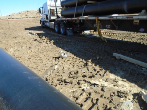 A parked truck with a load of pipes. Next to the truck, a dropped white helmet indicates the location of the victim.
