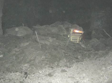 A mechanical scaler partially covered by debris from a mine roof fall.