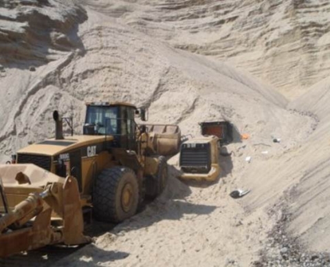 A front-end loader partially covered by a sand bank