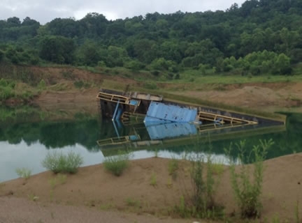 A partially submerged dredge after it capsized into the water.