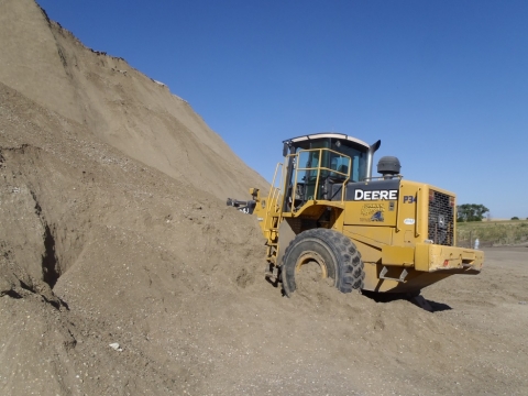 A front-end loader that is parked with its front against a sand bank