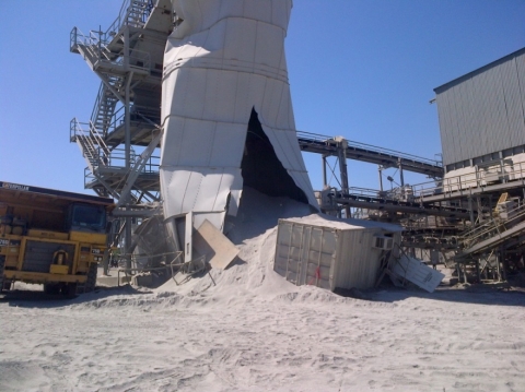 A sand silo that is cut on one side spilling debris