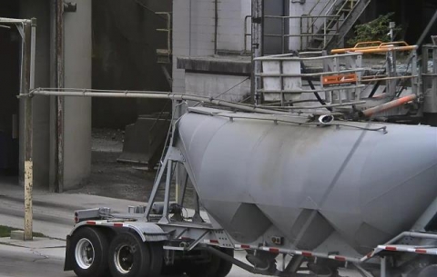 A bulk tanker truck with a metal rack hang over it.