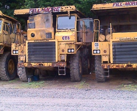Haul trucks parked inline, one with a open hood