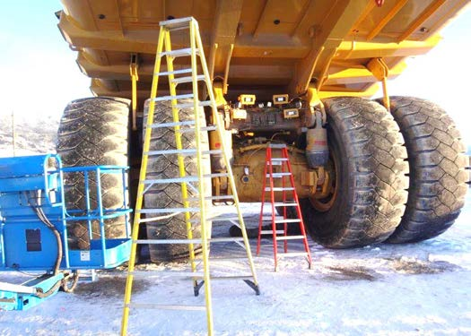 View from underneath a haul truck, four huge tires an plenty of room for a person to walk around