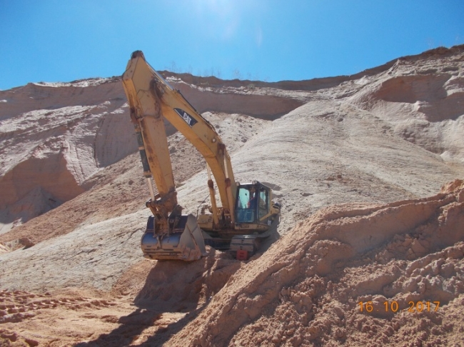 A haul trucks showing when the cab of the excavator was struck by material falling from a 65-foot bank failure.