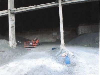Accident scene where two miners were attempting to repair a crane rail in a storage building while inside a man lift basket. While raising the man lift, the basket snagged on a beam.
