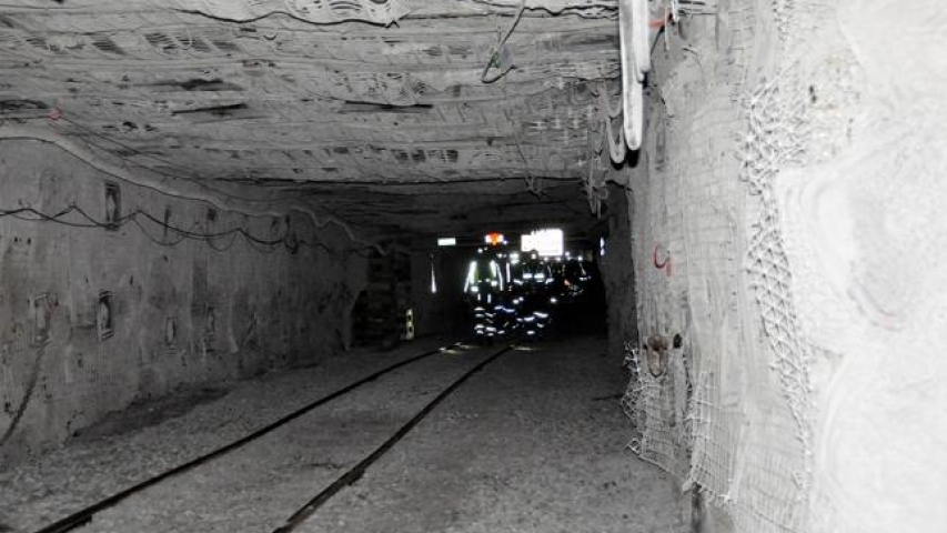 Miner's reflective clothing shining at dark end of mine shaft