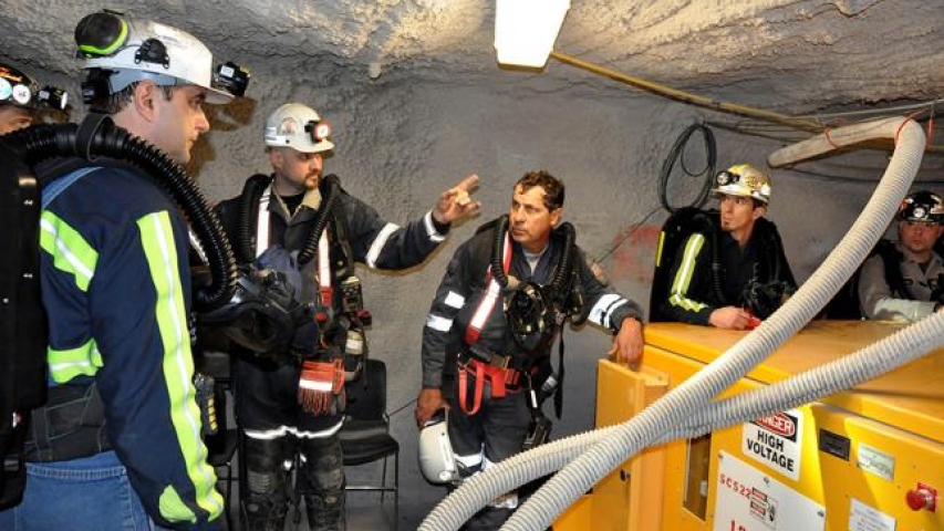 Miner demonstrating to other miner's how to operate a machine