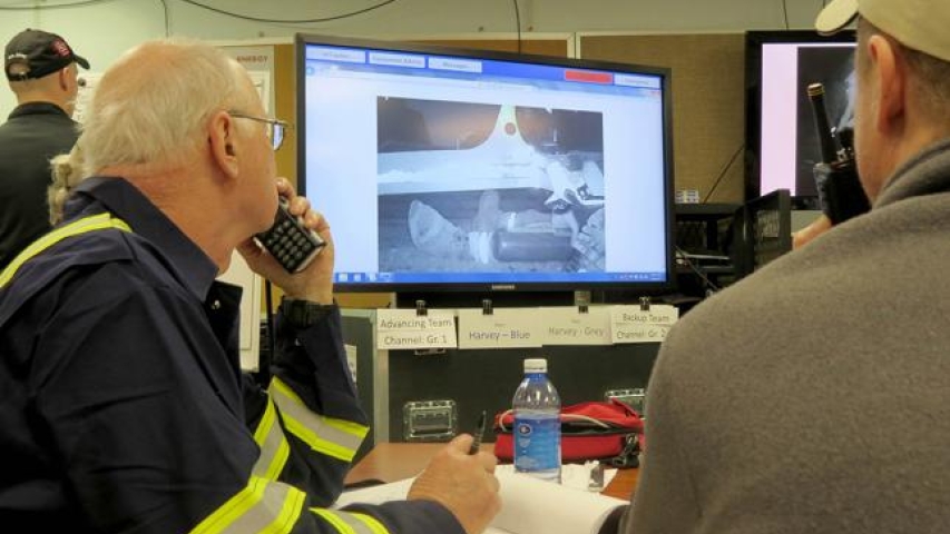 Men observing mining operations on computer monitor